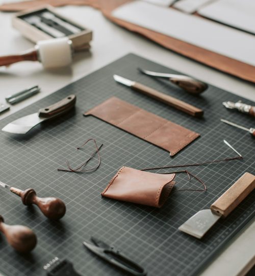 Close-up of tools and materials on a leather crafting workspace, showcasing artisanal craftsmanship.