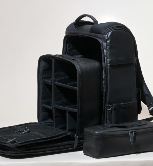 Sleek black leather camera bag showcasing compartments on a white background.